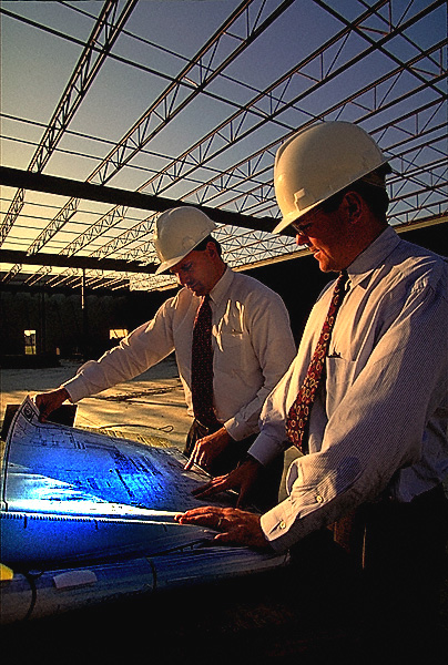 men wearing hardhats looking at blue blueprints
